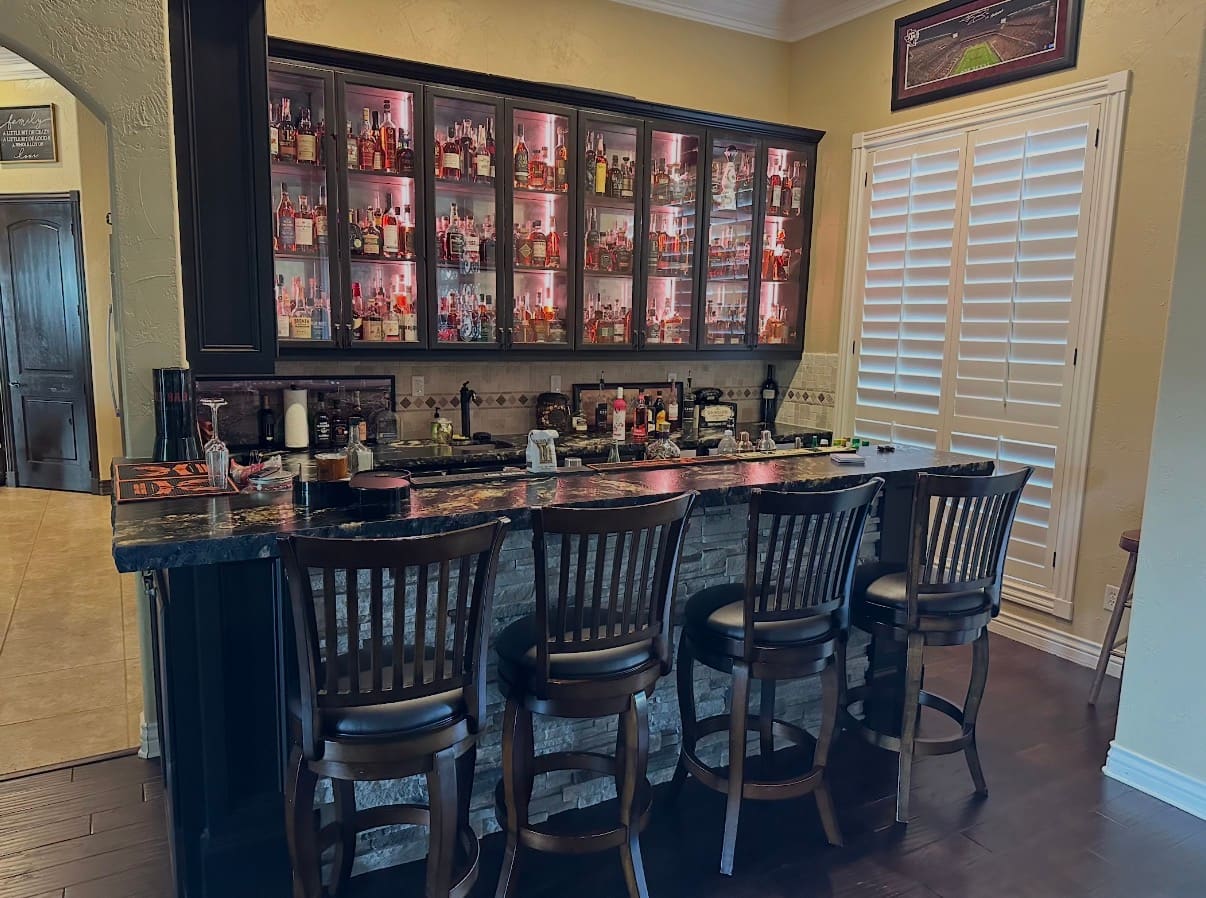 Bar Buildout — backlit home bar with dark cabinetry and stone front, College Station, TX